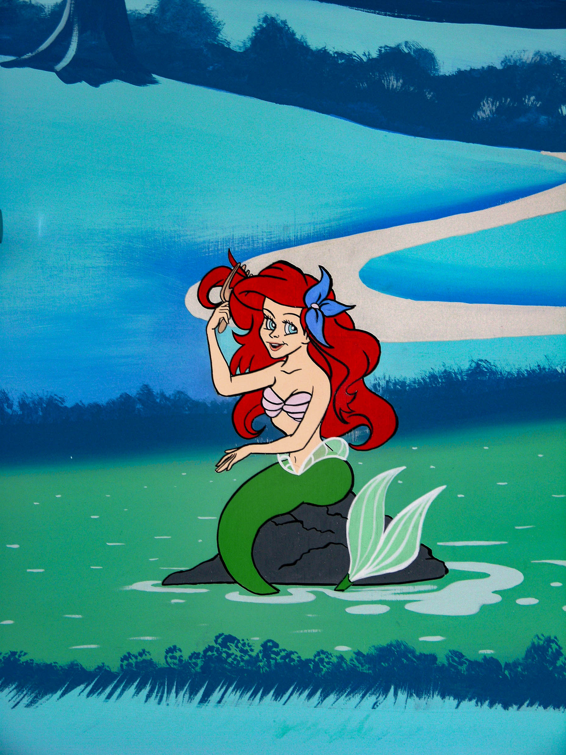 The Little Mermaid sitting on a rock, combing her long red hair
